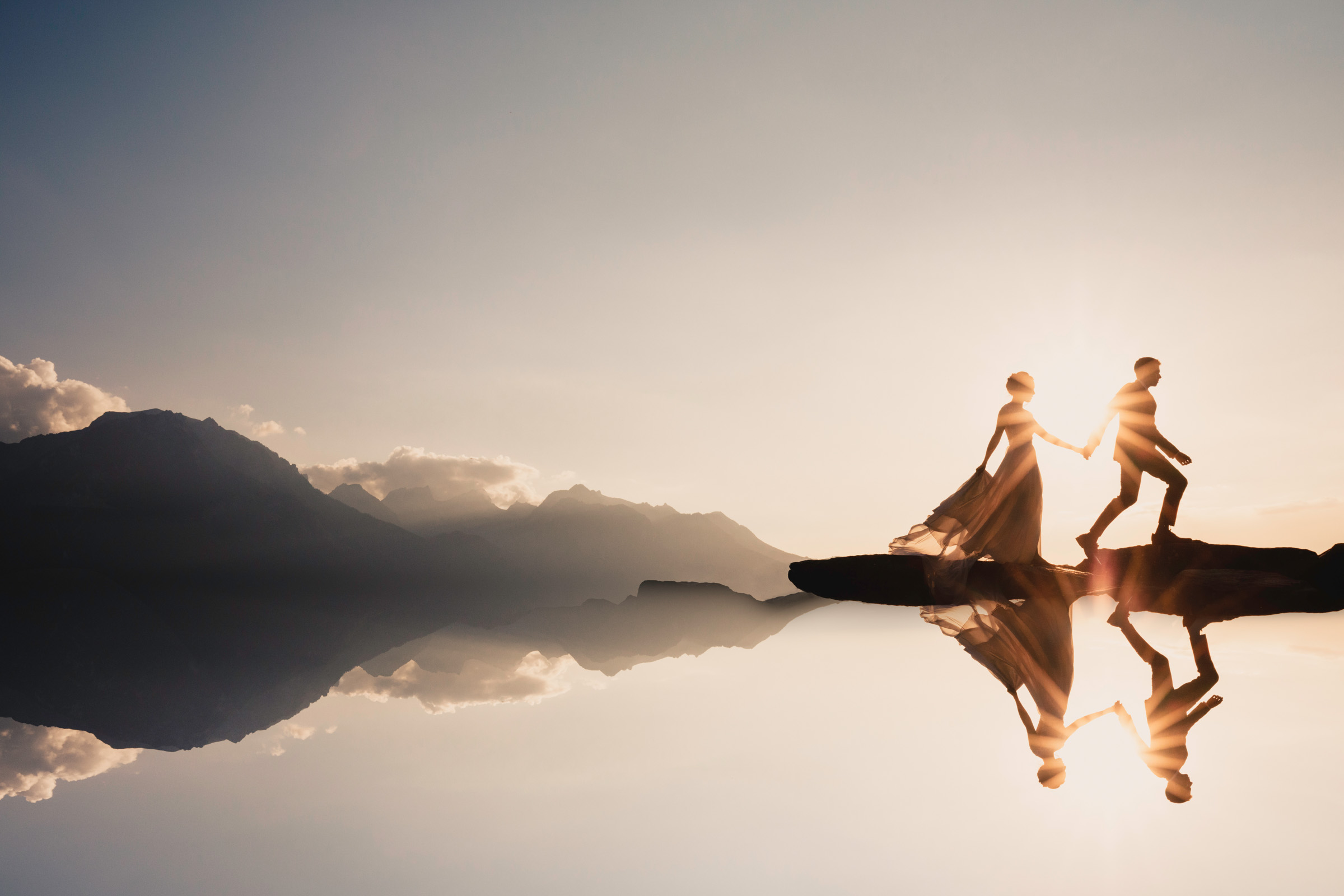 Silhouette of couple walking in horizon with sun flare by Marissa Joy of Los Angeles