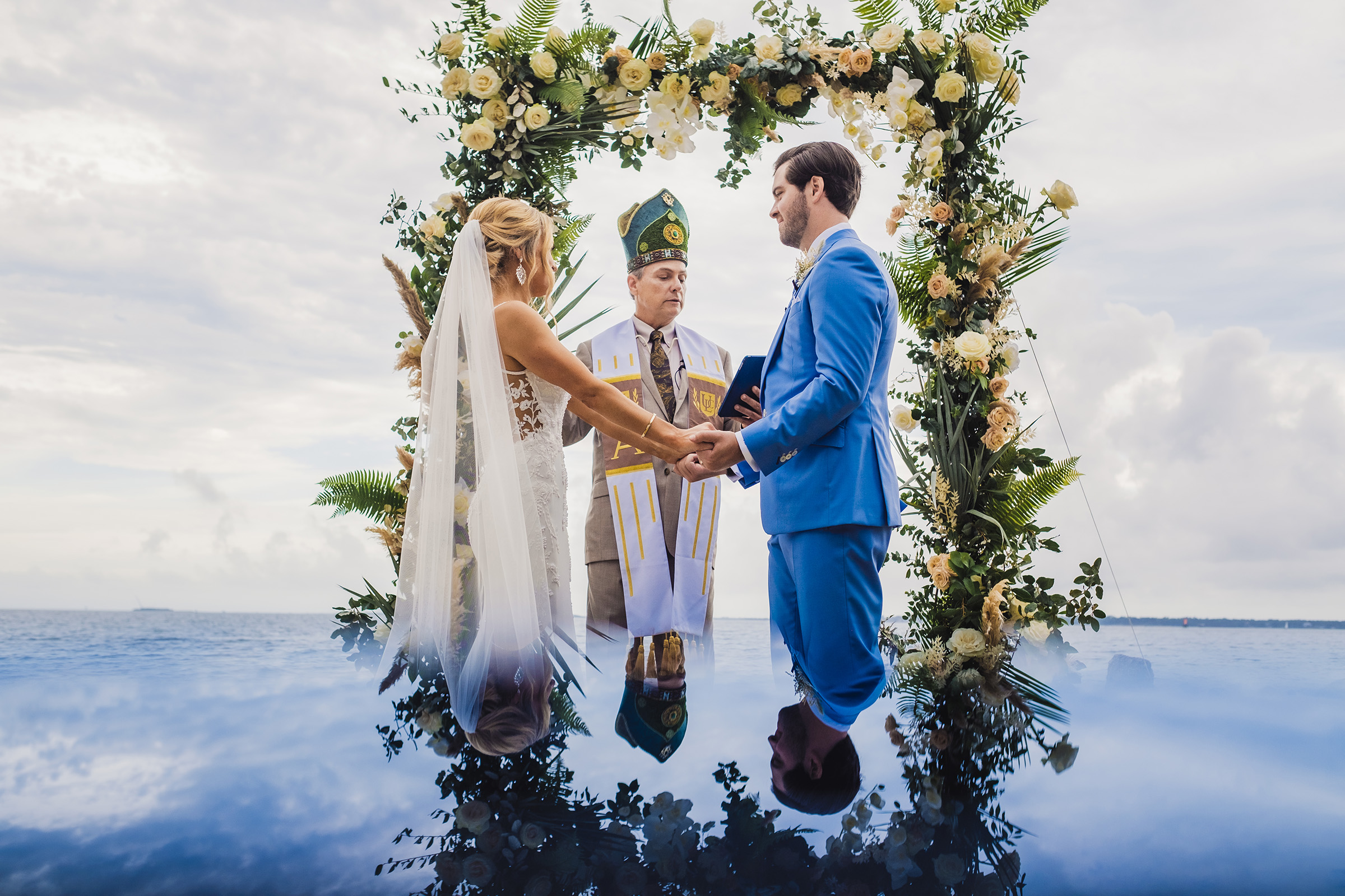 couple-ceremony-with-officiant-under-floral-arbor-with-reflection-photo-by-chrisman-studios