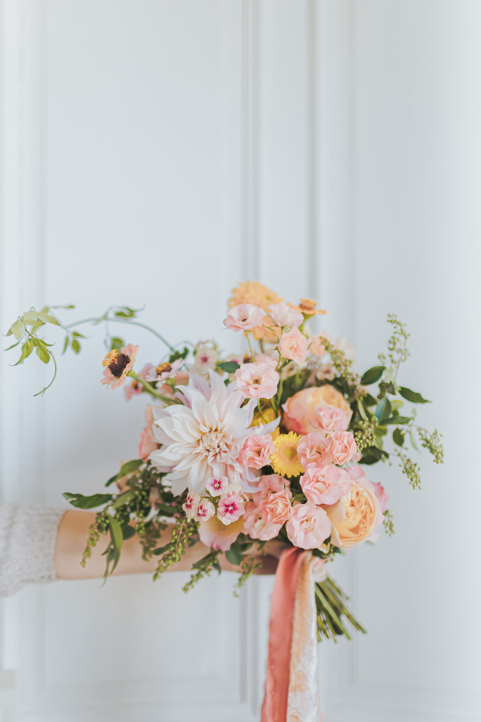 bride-holding-pastel-colored-spring-bouquet-with-ribbons-photo-by-carolina-serafini-photographer