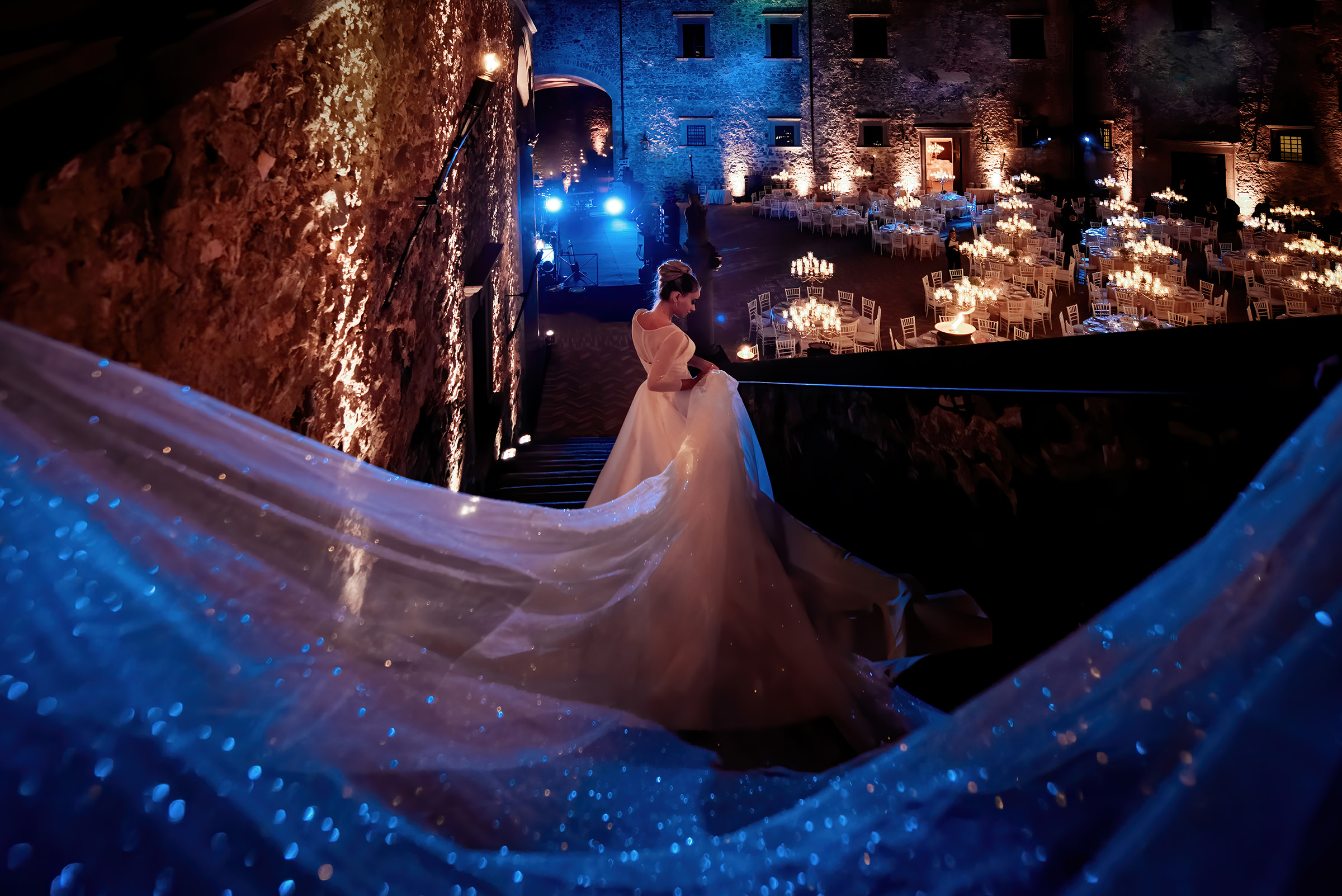 bride-entering-candlelit-reception-space-with-trailing-sparkling-train-photo-by-emiliano-russo-photography