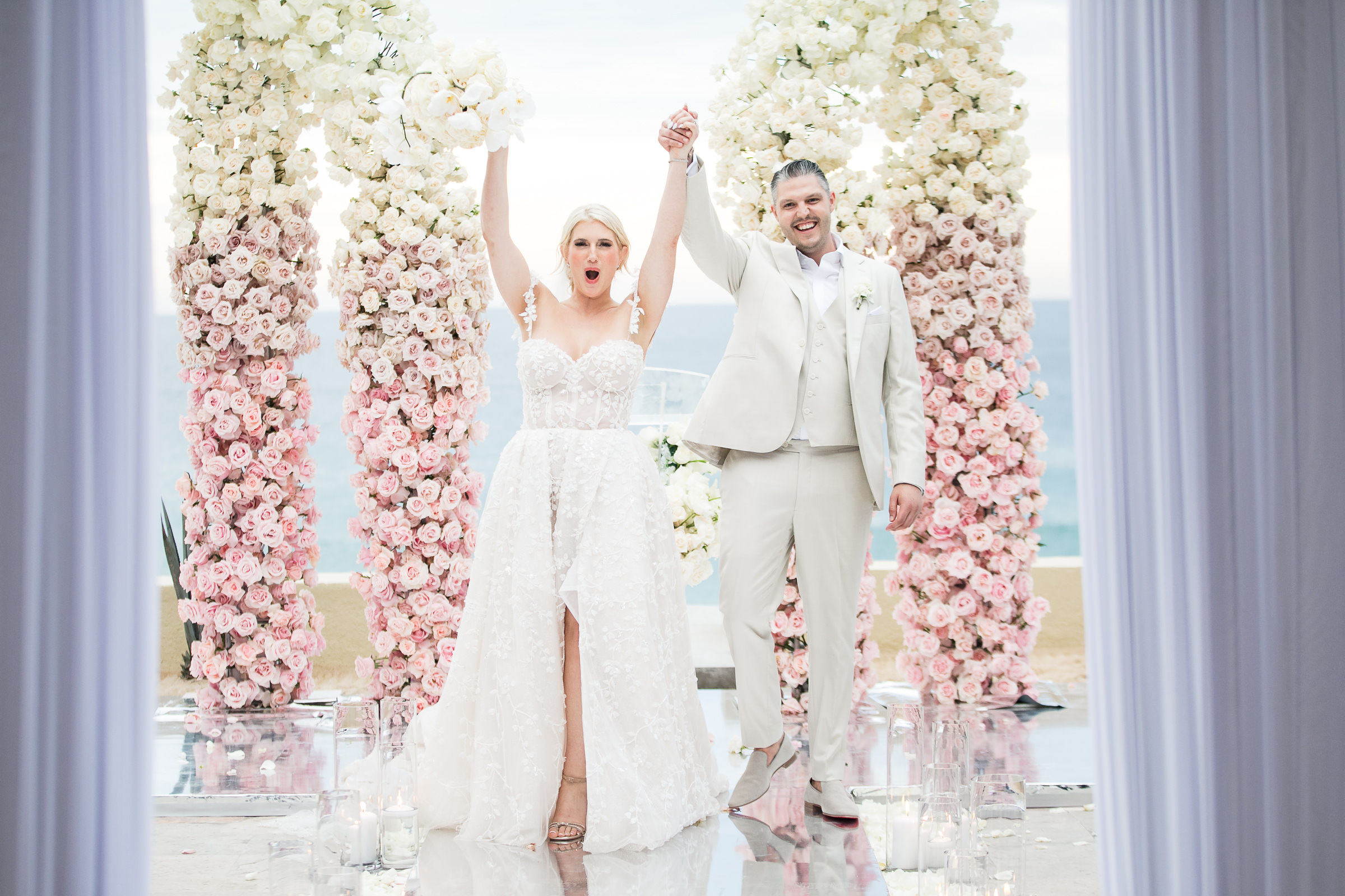 Just married couple at arbor of pink and white roses