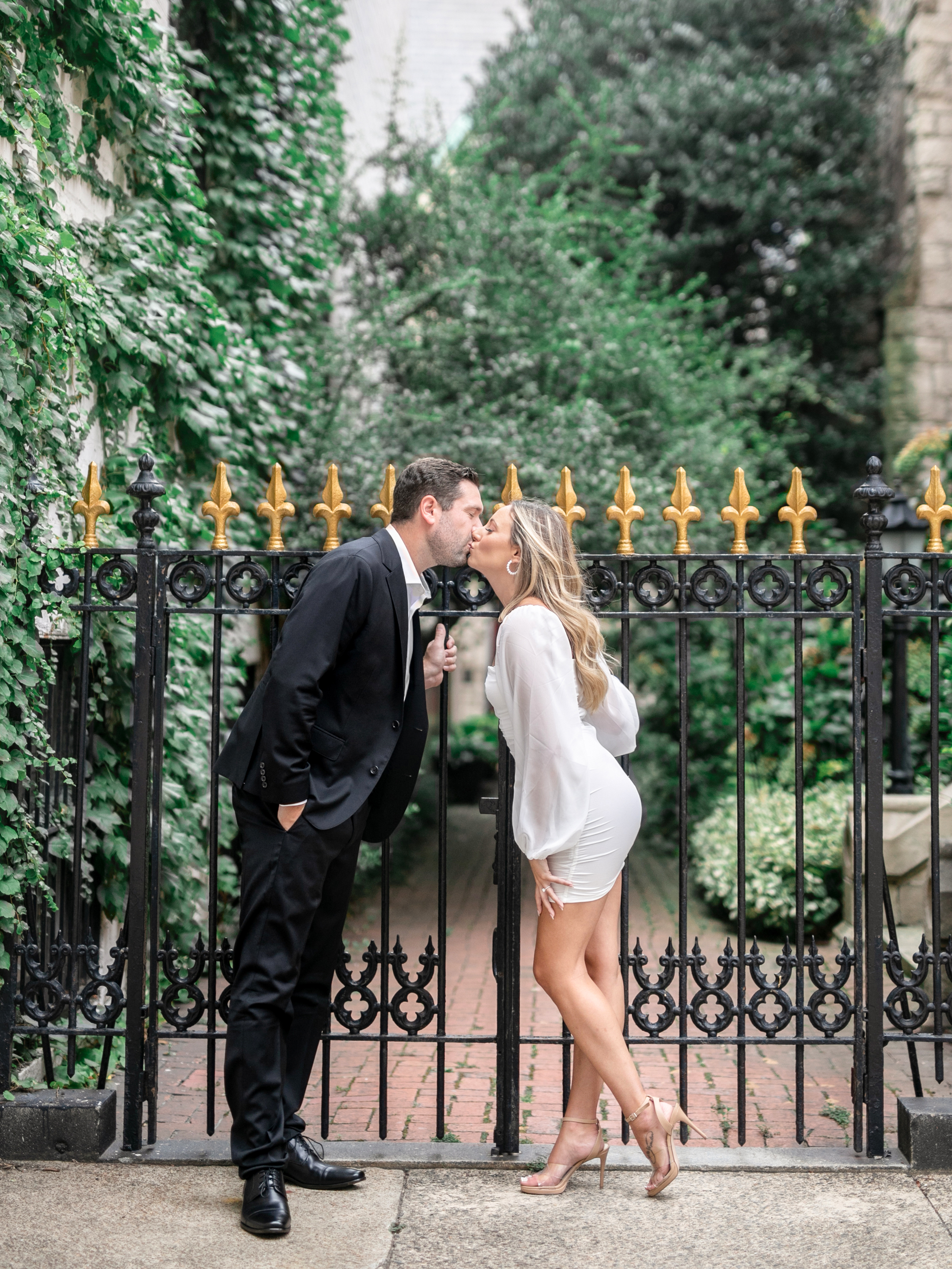 leaning-in-kiss-against-wrought-iron-fence-photo-by-anna-schmidt-photography