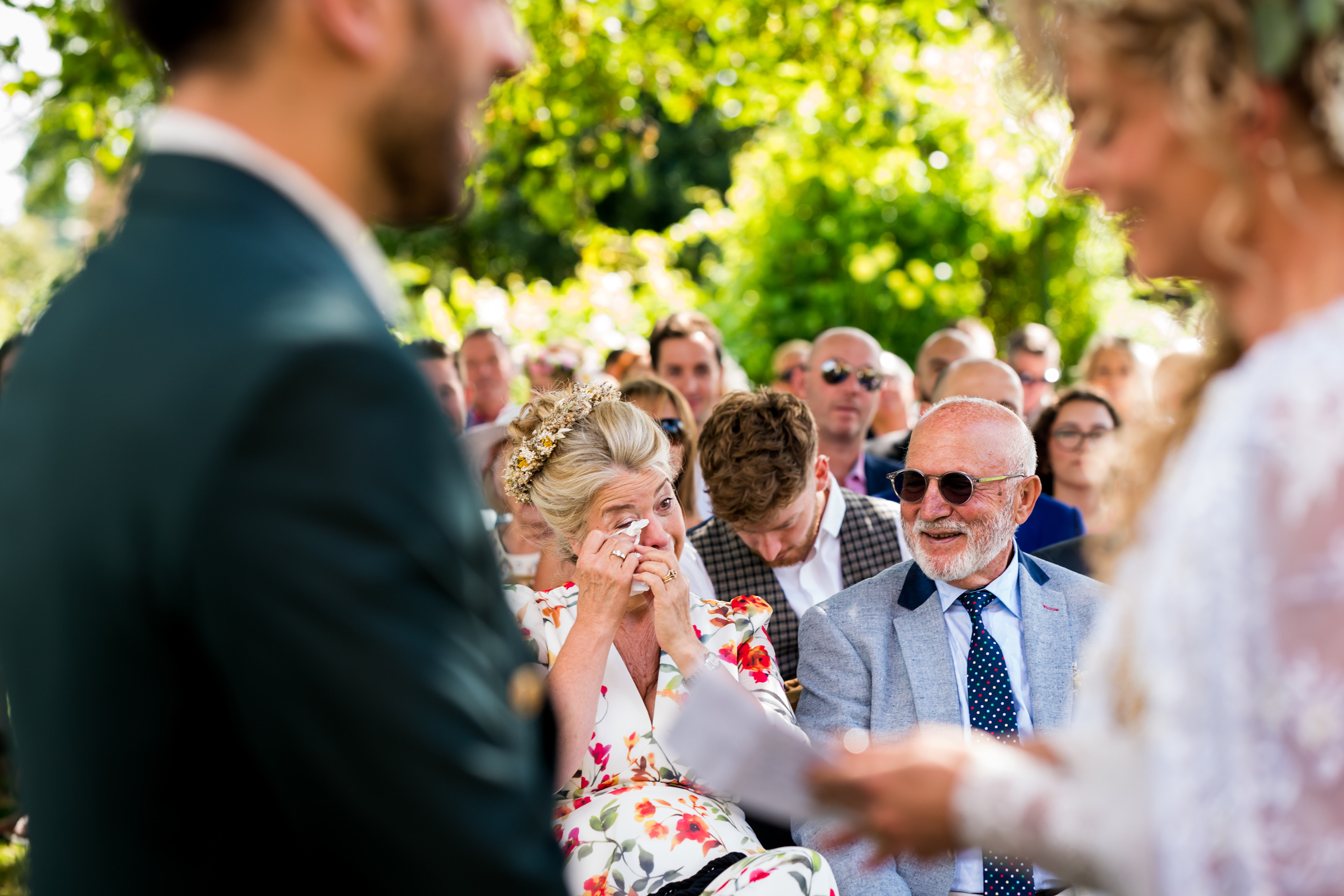 Bride and groom exchange rings while family and friends watch