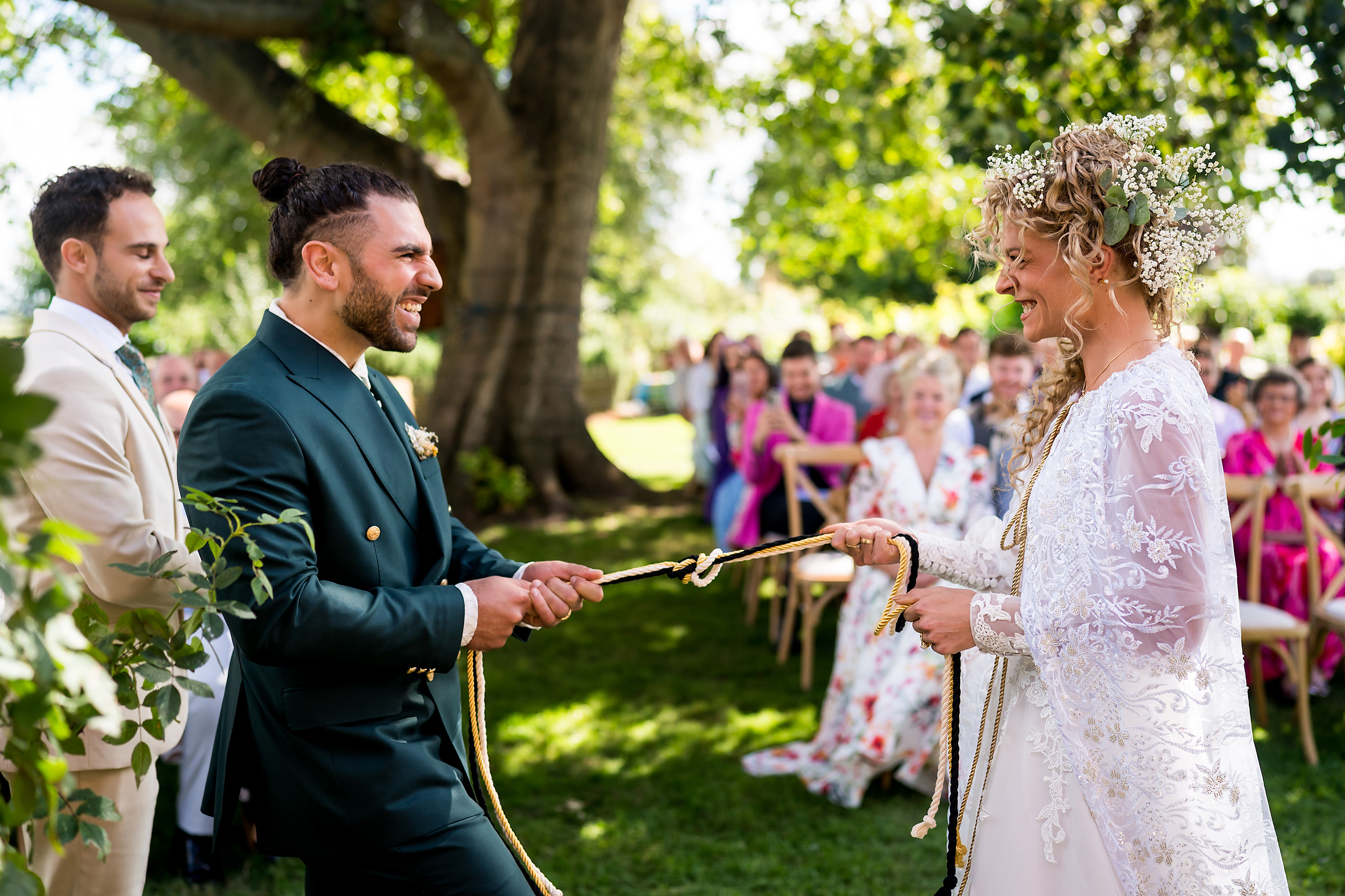 Bride and Groom pull on a gold knotted rope to seal their union