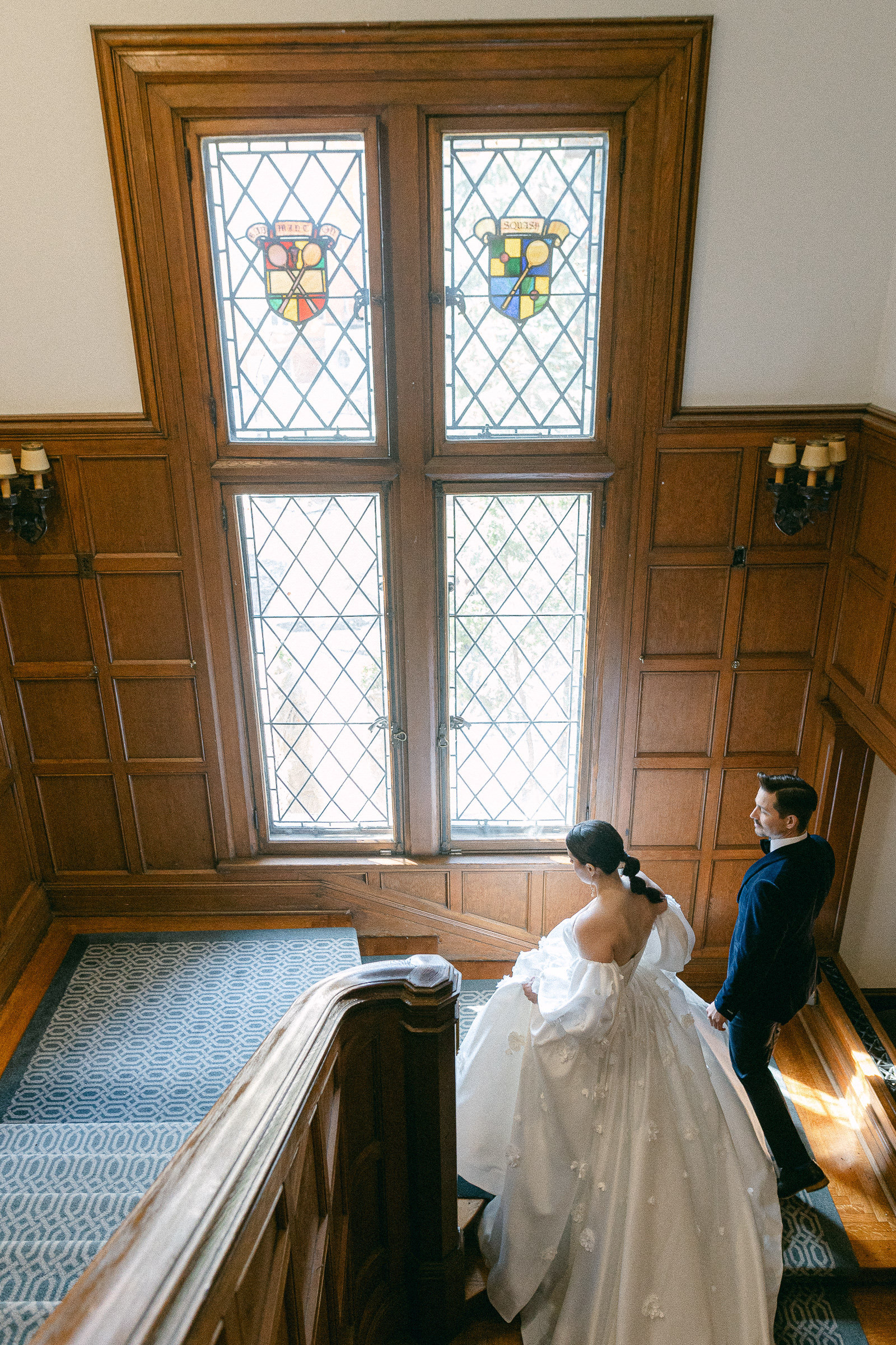 bride and groom walking upstairs hand in hand-Sophie Asselin