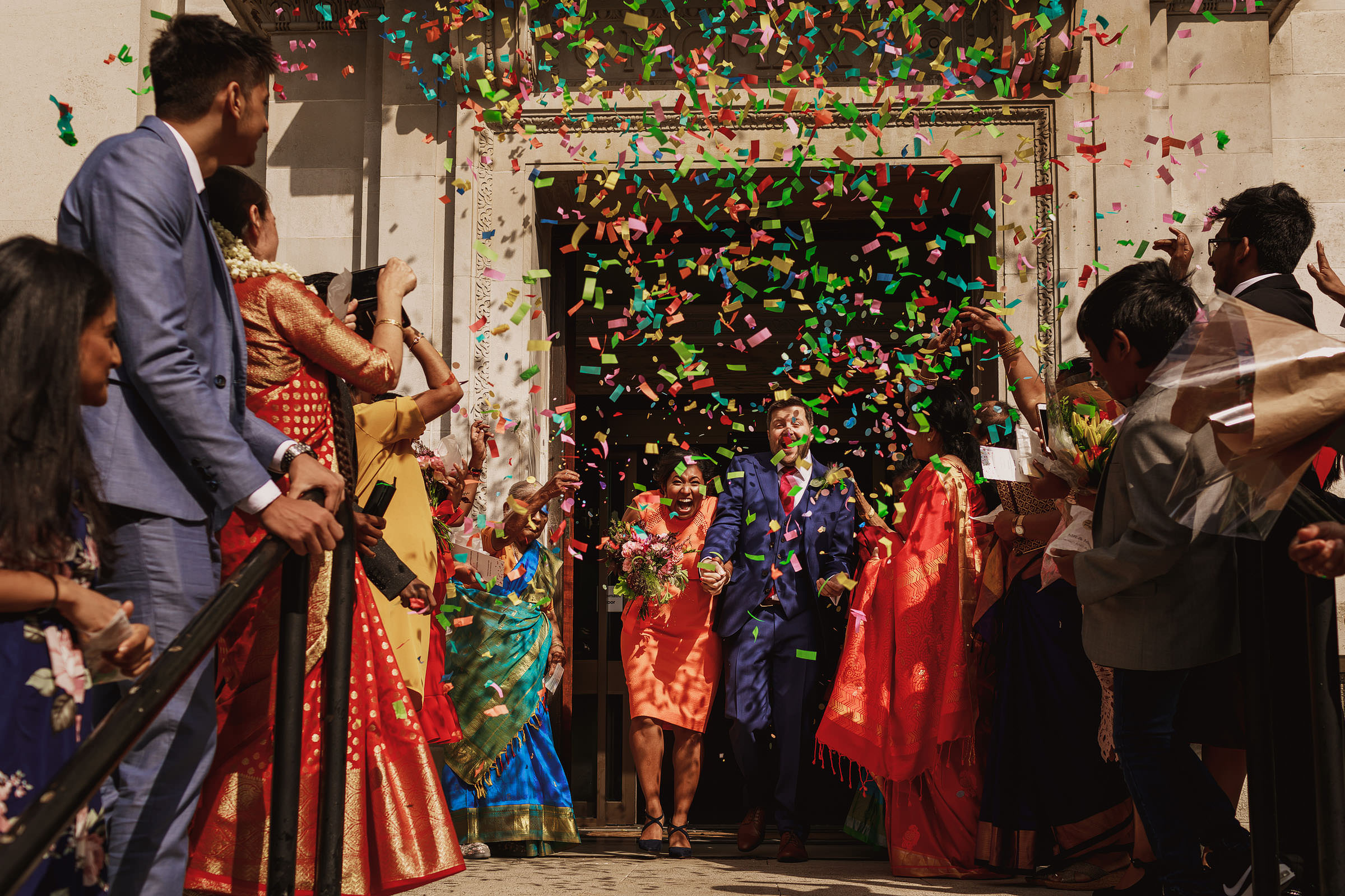 Couple exits under colorful confetti photographed by f5 Photography - London