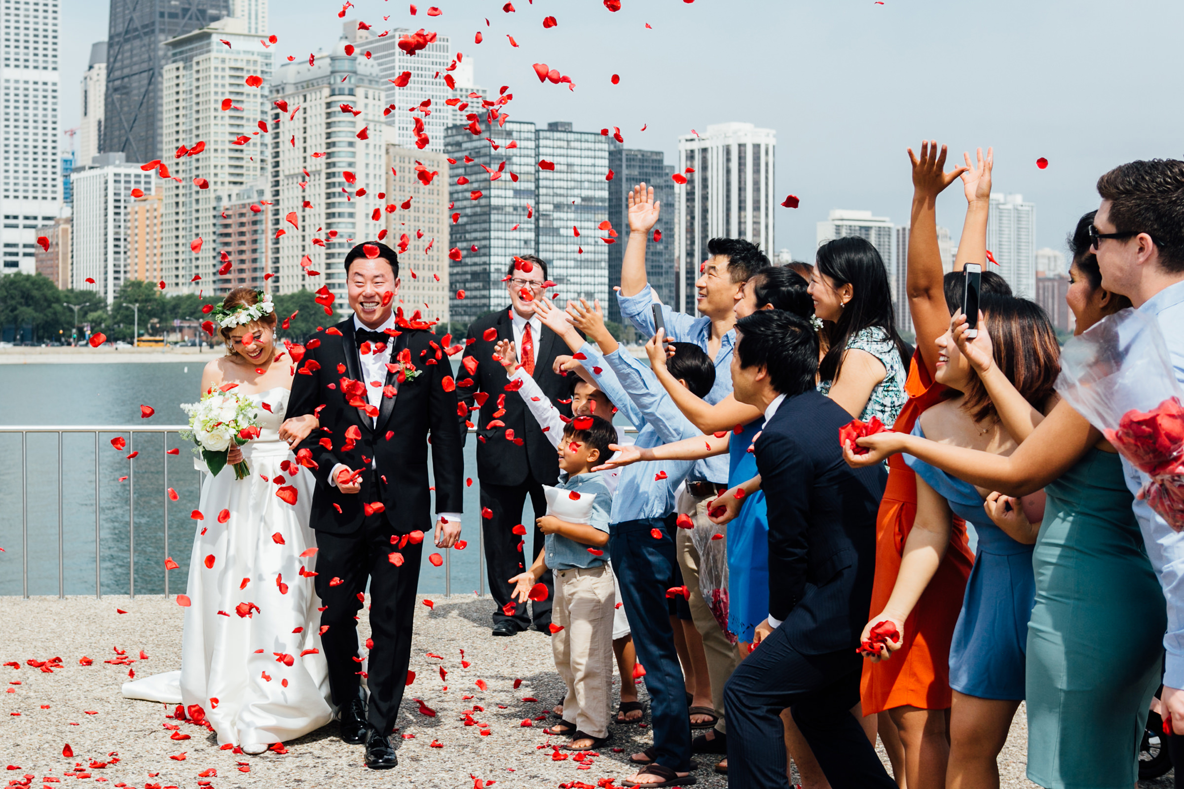 guests-showering-happy-couple-with-red-rose-petals-against-city-skyline-photo-by-syphotography