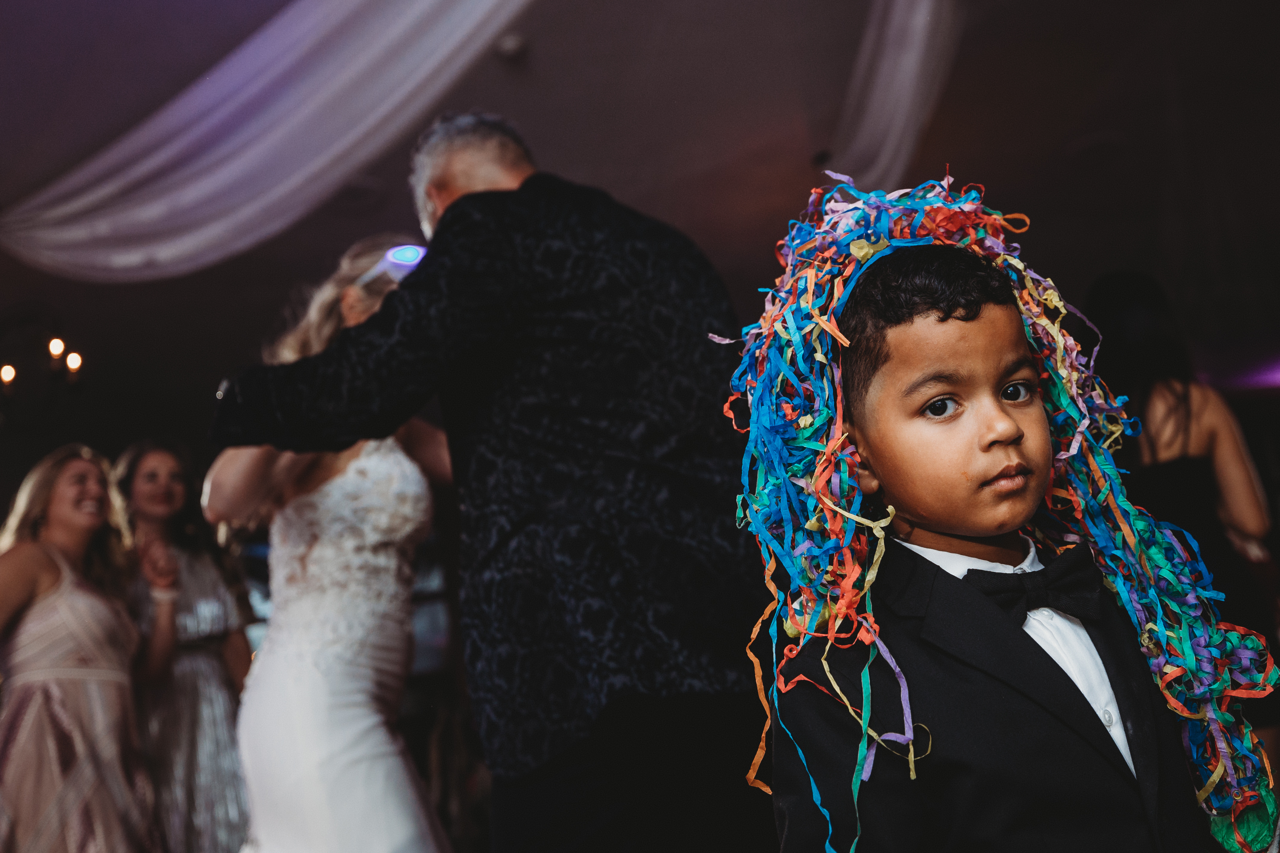 Award winner, boy in tux with colorful paper on head - photo by Carrie Kizuka Photography, LLC