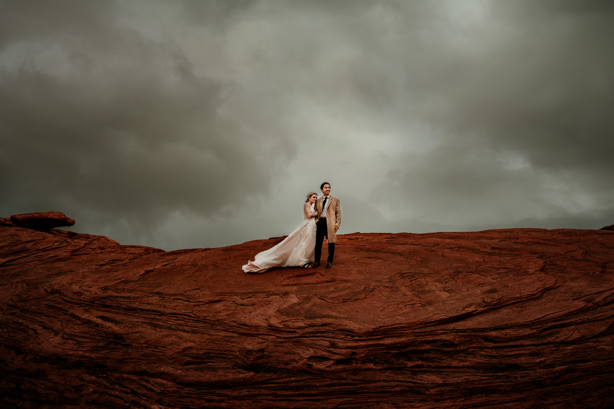 bride and groom portrait on red rocks under a dark cloudy sky- photo by Sacramento wedding photographer As the Crow Flies bride and groom portrait on red rocks under a dark cloudy sky- photo by Sacramento wedding photographer As the Crow Flies