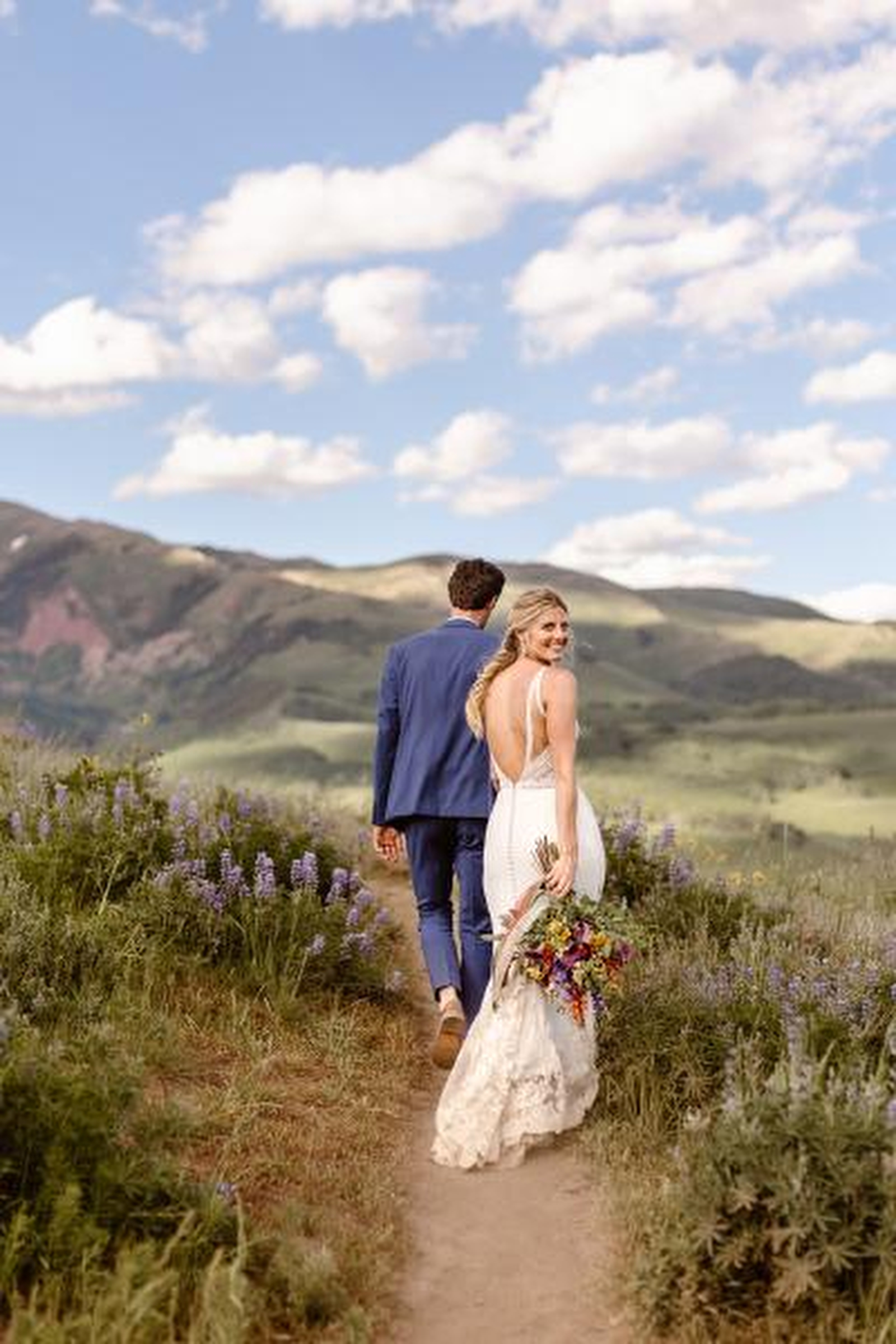 Couple walking in fields of flowers - photo by Colorado elopement photographer Andrea Enger Photography