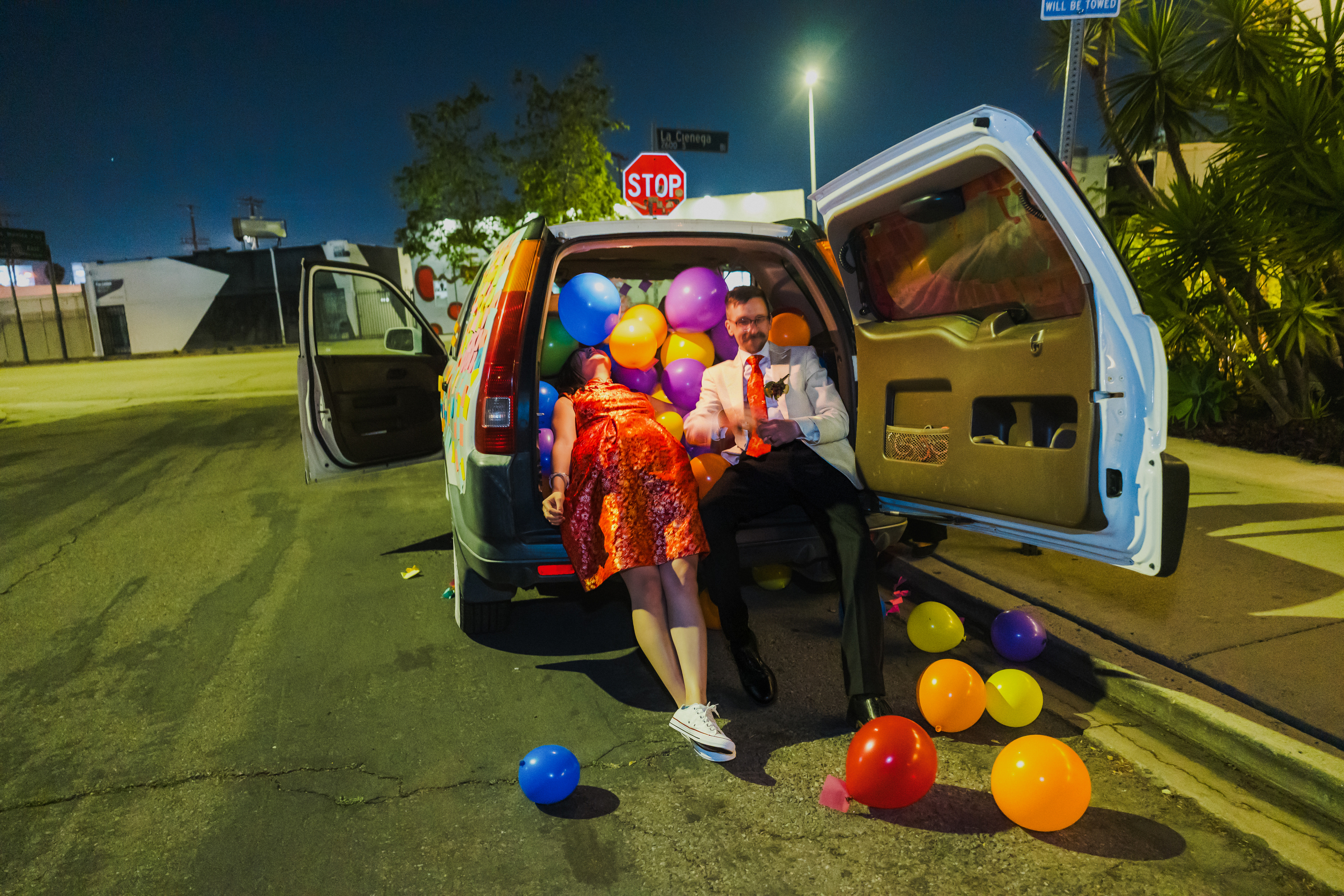 Bride and groom resting in car with balloons spilling out - photo by LA documentary wedding photographer Annie Bang Bride and groom resting in car with balloons spilling out - photo by LA documentary wedding photographer Annie Bang