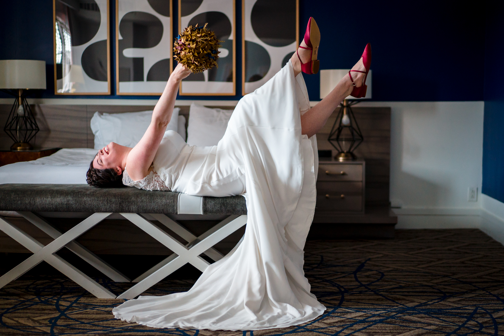 Bride laughing on hotel bed - photo by Bee Two Sweet