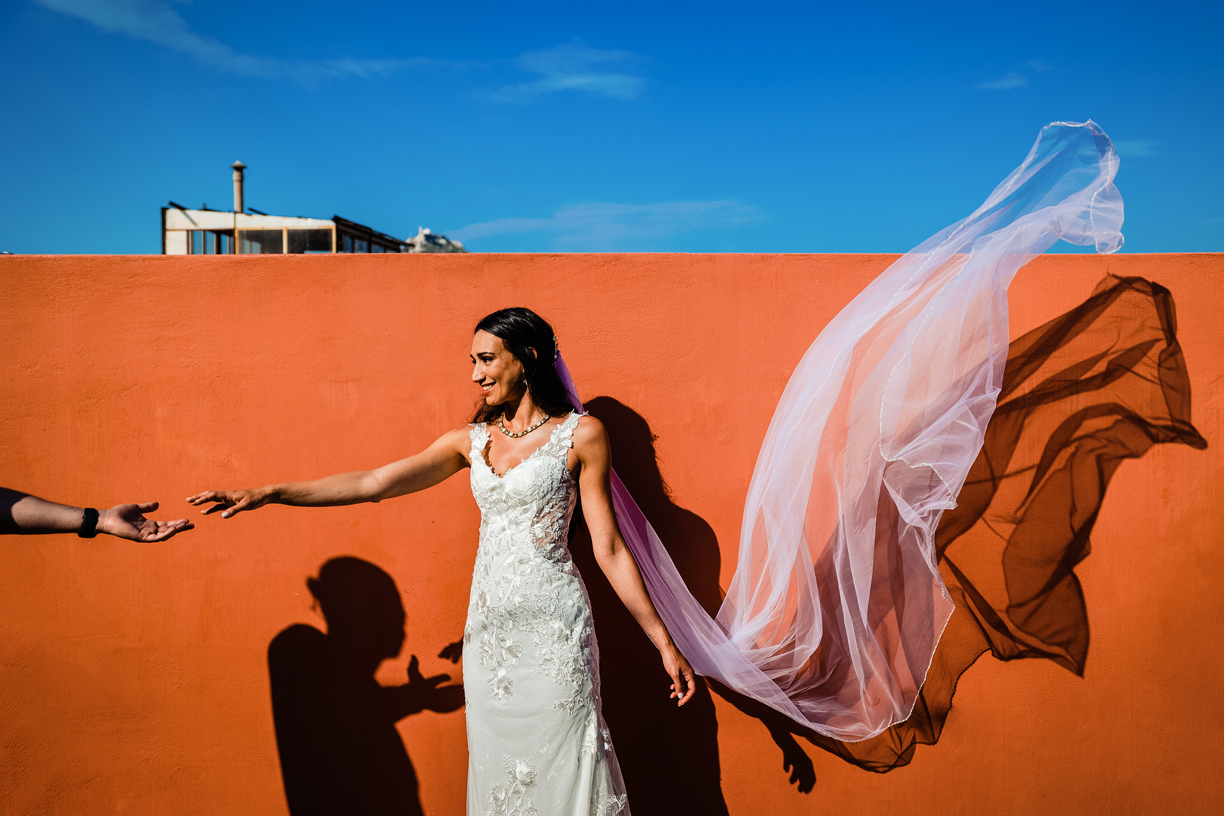 Bride against orange wall and sky - photo by Dimi & Wallace