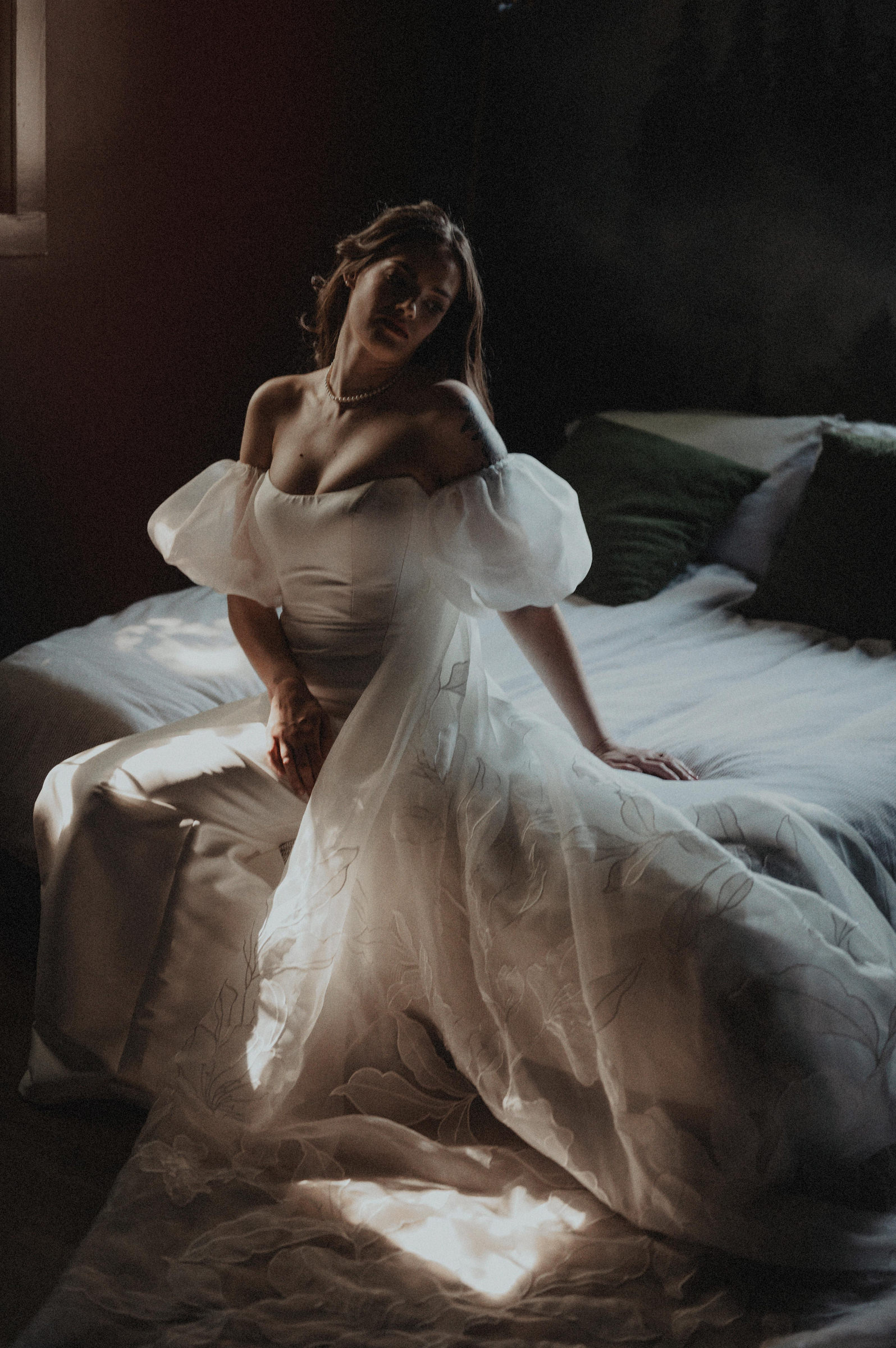 Bride sitting on bed in puffy sleeves gown - photo by Carolina Rivera Photography