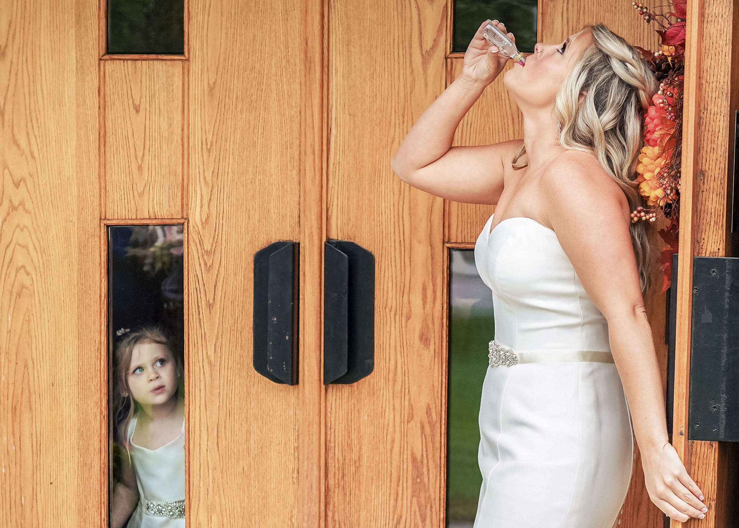 Bride drinking while little girl looks on - photo by sally carpenter photography