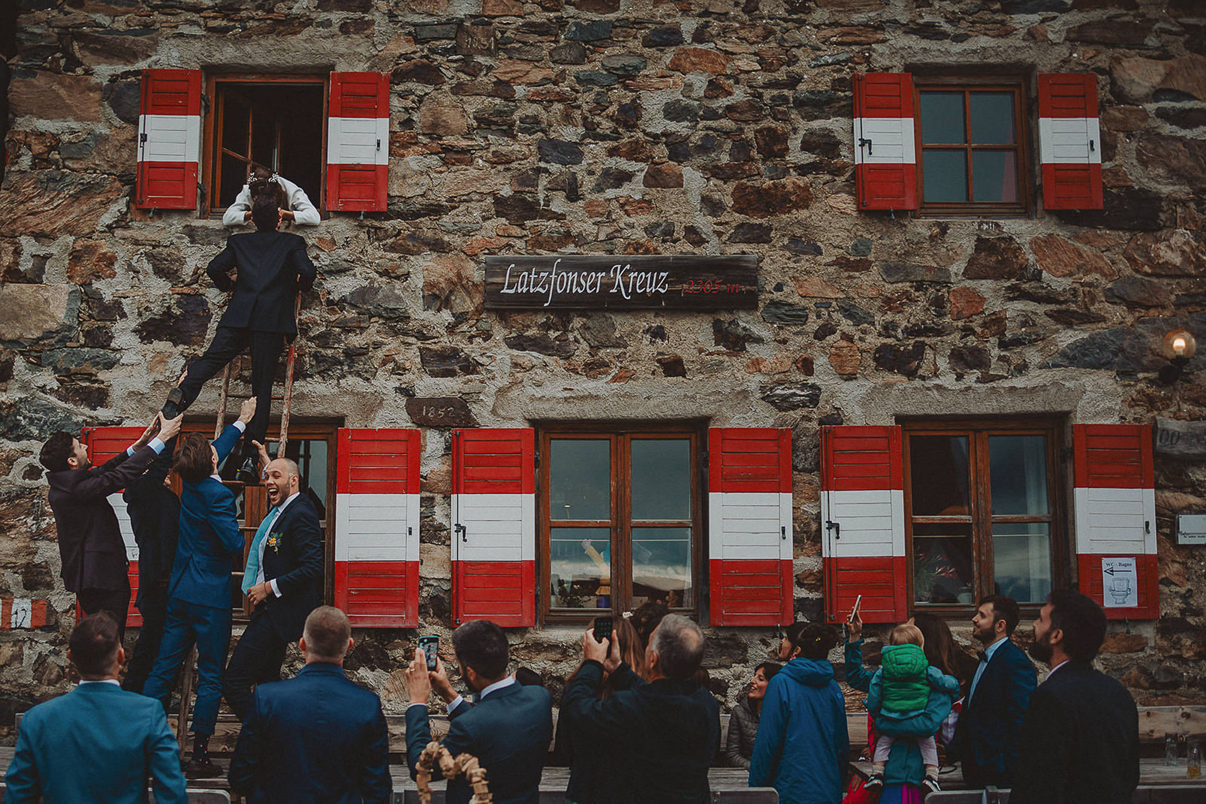 Groom climbing ladder to kiss bride - photo by Livio Lacurre Photography
