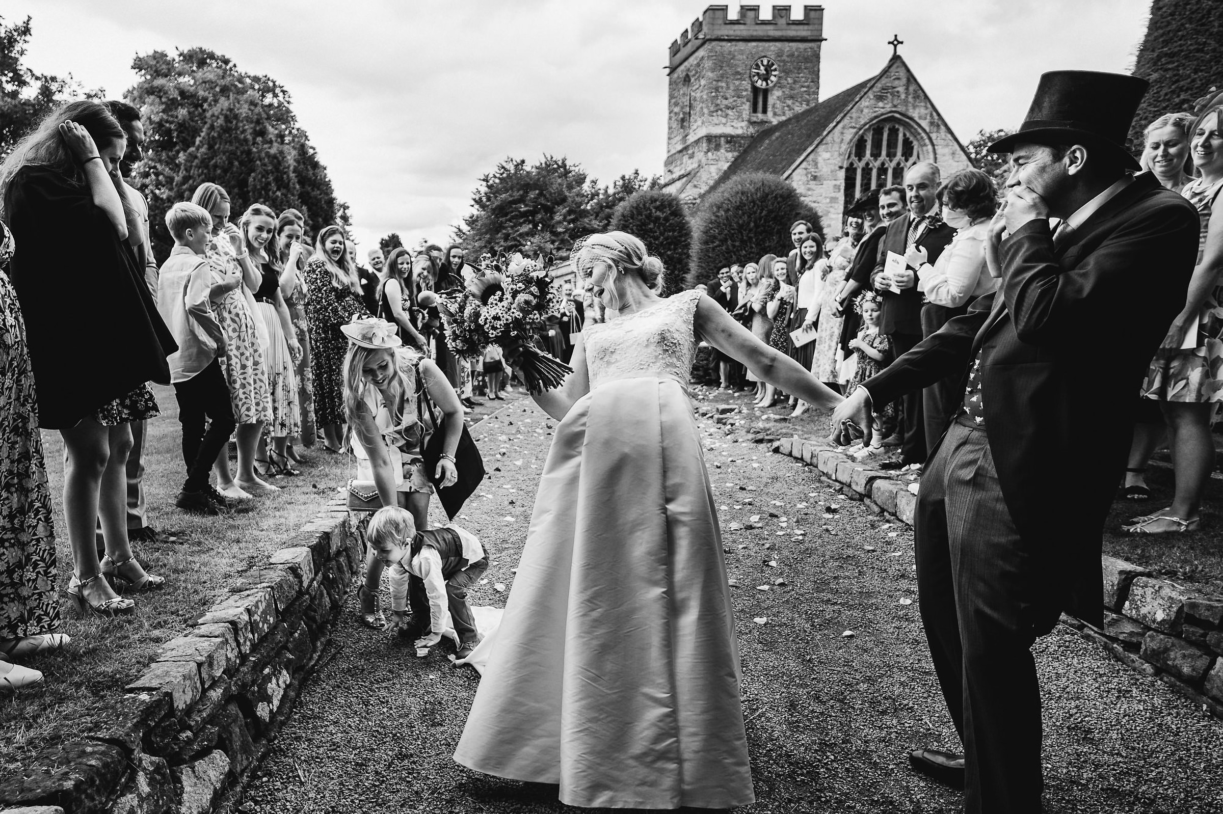 Little boy stepping on bride dress during exit - photo by UK documentary wedding photographer Andy Gaines Photography