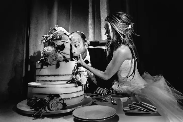 groom takes first bite of cake without fork - photo by callaway gable