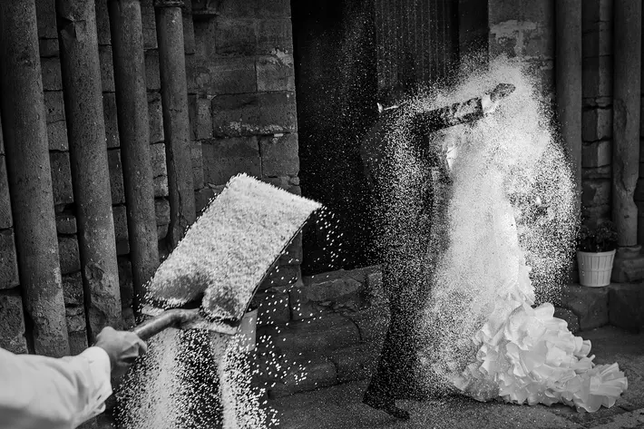 black-and-white-shovel-of-rice-during-bride-and-groom-exit-worlds-best-wedding-photos-victor-lax-spain-wedding-photographers