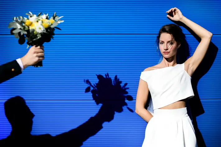 Shadow of bouquet being given to bride modern two piece gown - photo by Julien Laurent Georges