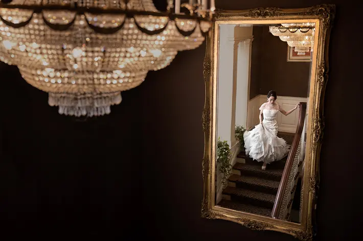 Bride reflected in gold-leaf mirror on elegant stairway - photo by David and Sherry - top Canadian photographers 
