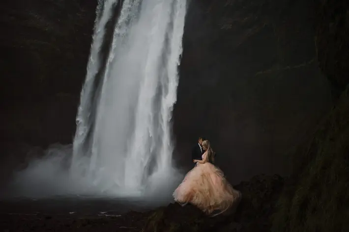 Bride in pink tulle ballgown with groom at bottom of waterfall - photo by Gabe McClintock - Alberta, Canada