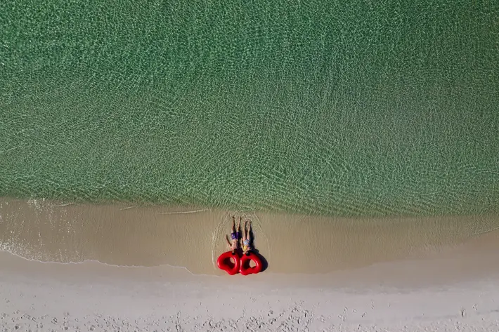 Couple lying on beach with heart shaped floaties - photo by ModernMade - Florida