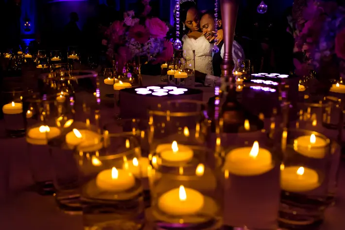 Portrait of bride and groom at table through candlelight - photo by Jide Alakija - NYC, New York