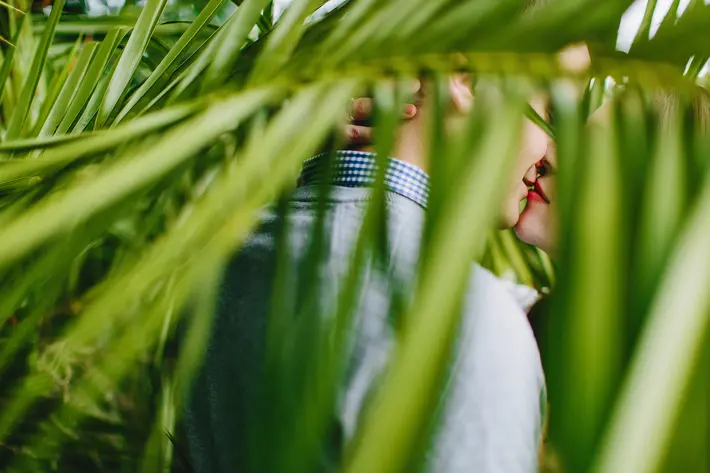 Couple sneaks a kiss behind ferns - photo by Ruan Redelinghuys 