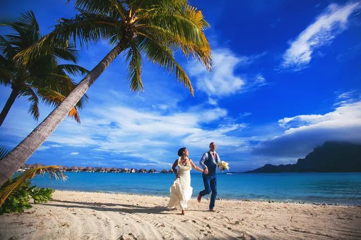 Couple running on the beach in Bora Bora - photo by Callaway Gable
