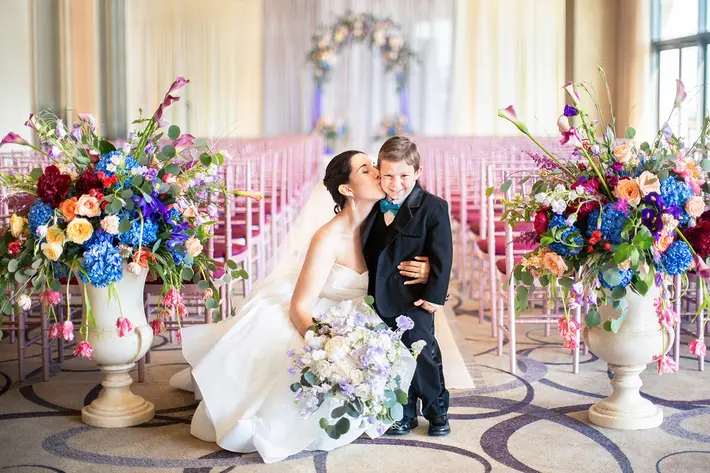 Bride kissing ring bearer on aisle runner among flowers - photo by Anna Schmidt DC