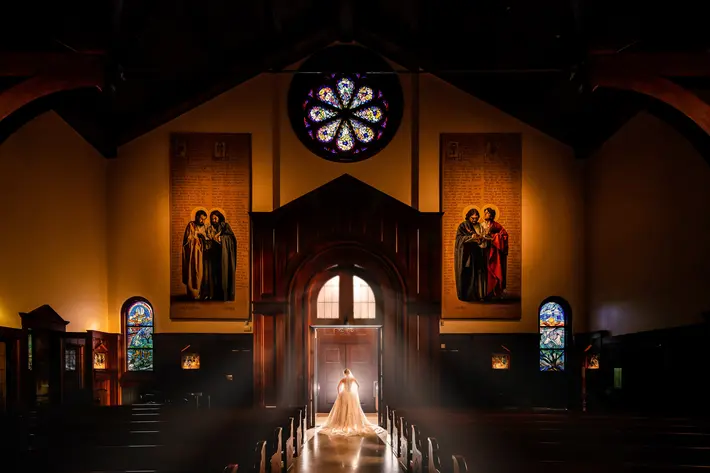 Bride standing in church entrance with light flooding in around her - photo by M.Hart Photography - Los Angeles