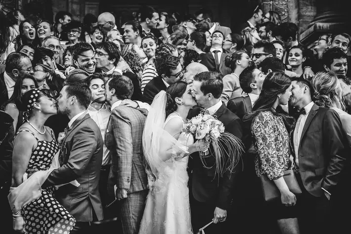 Couple kissing in a crowd of people kissing - photo by Julien Laurent-Georges - French wedding photographer