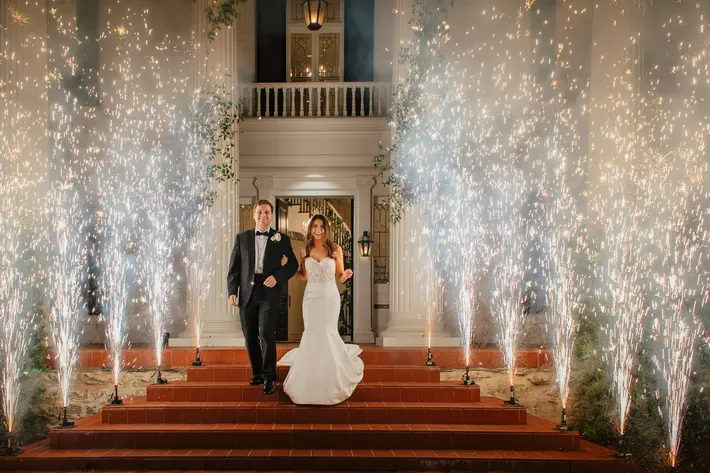 couple-descend-steps-against-lit-sprinkler-spray-carolines-collective