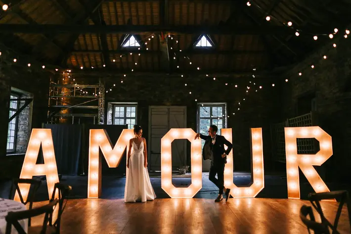 bride-and-groom-portrait-in-front-of-light-letters-amandine-ropars-france