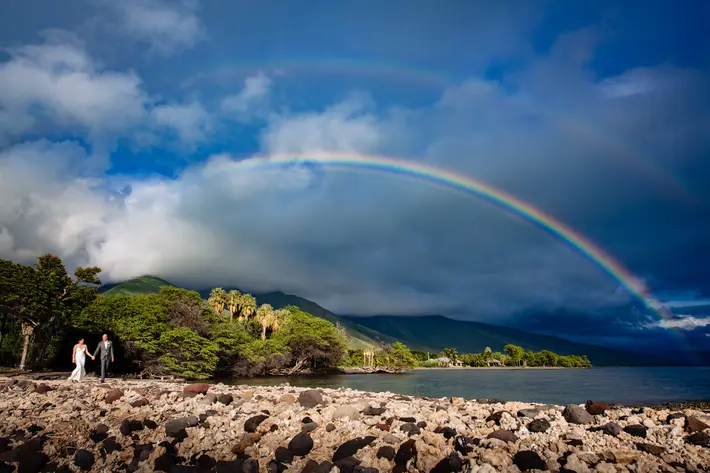 Bride and groom walking against double rainbow, Maui, Hawaii - photographed by Angela Nelson