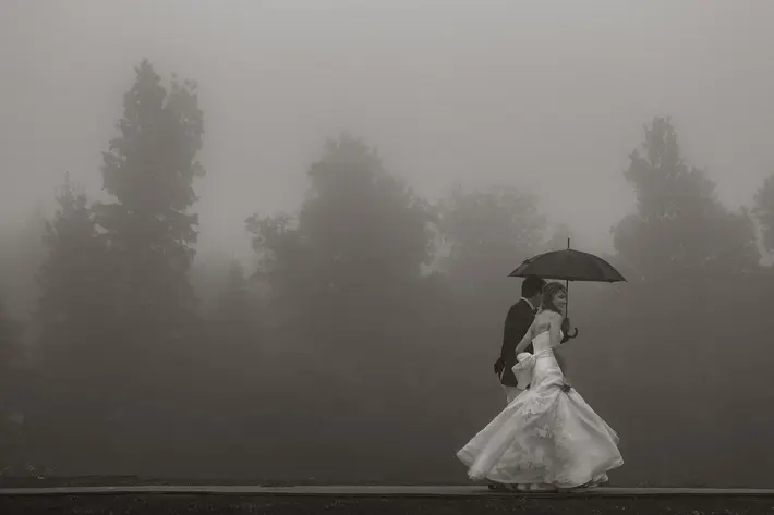 Romantic photo of bride and groom walking in the fog and rain by Joel and Justyna, Ottawa wedding photographers