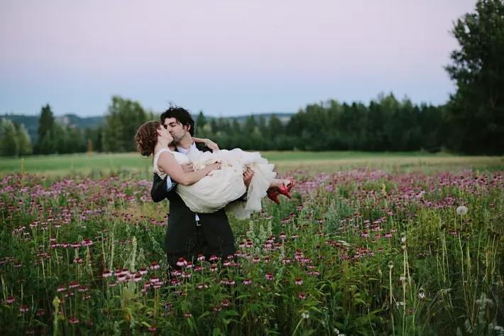 groom-carrying-bride-in-field-of-flowers-Farmgate-Homestead-Trout-Lake- Washington-jonas-seaman-photography