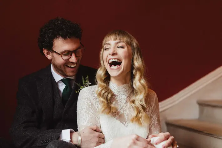 bride-with-curly-blonde-hair-and-bangs-groom-laughing-white-cat-studio