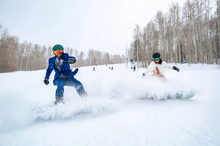 Bride and groom snowboarding at winter wedding - photo by Andy Madea