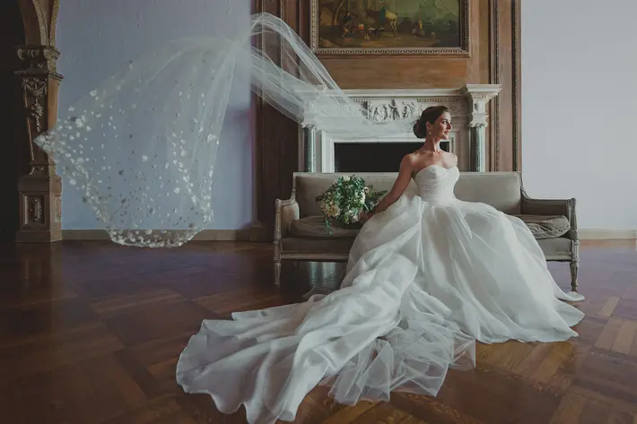 seated-bride-in-strapless-luxury-gown-with-long-fluffy-train-and-sparkling-veil-photo-by-lauren-cate-photography