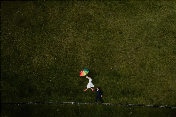Drone shot of couple with rainbow umbrella Liam + Bee