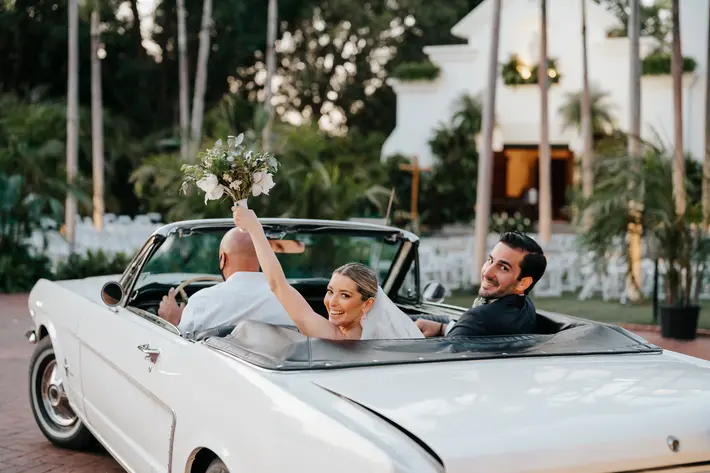 Bride waves her bouquet from back of Mustang, photographed by Ruben Parra, Miami