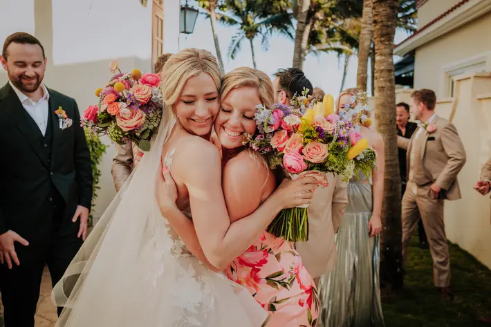 Bride and sister hugging and holding pink bouquets Ruben Chan Photography Quintana Roo photographer